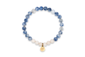 Natursteinarmband „Mondsee“ mit blauen Sodalithperlen, blau-weißen Mikroklineperlen, weißen Marmorperlen und einem goldfarbenen Edelstahl-Anhänger mit vertiefter Baumgravur auf weißem Hintergrund.